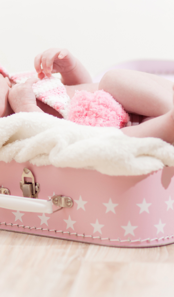 Милый младенец лежит в розовом чемодане