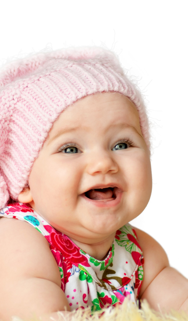 Милая маленькая улыбающаяся девочка в большой розовой шапке