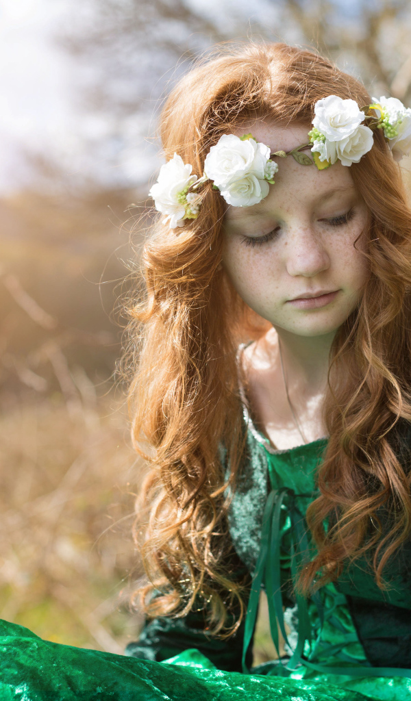 Милая рыжеволосая девочка в зеленом платье с венком на голове