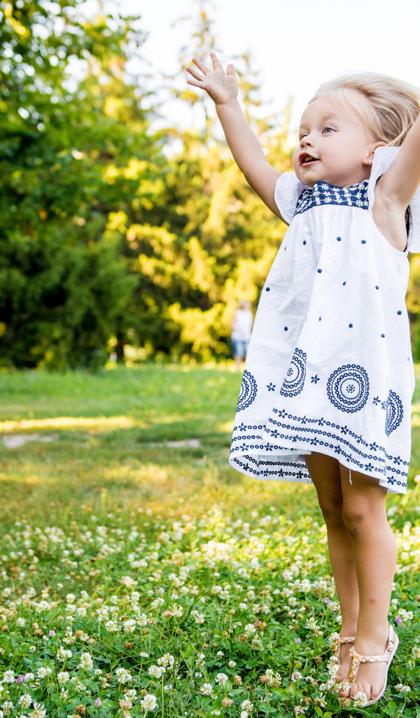 Девочка в красивом платье гуляет на зеленом лугу