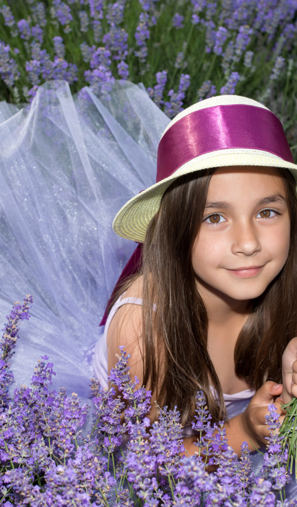 Девочка в шляпе лежит в фиолетовых цветах лаванды