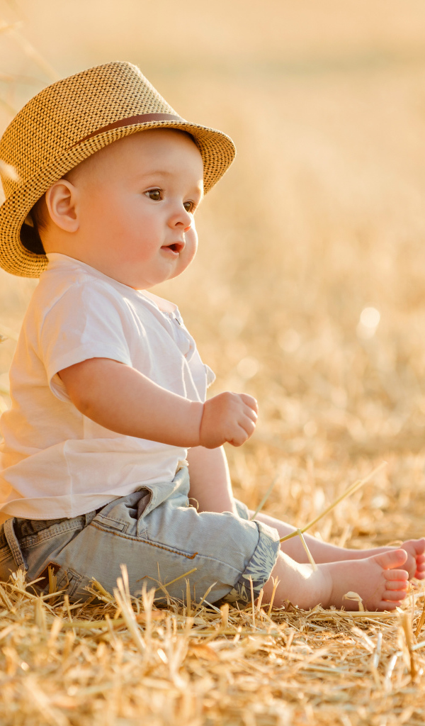 Маленький мальчик в шляпе сидит на себе