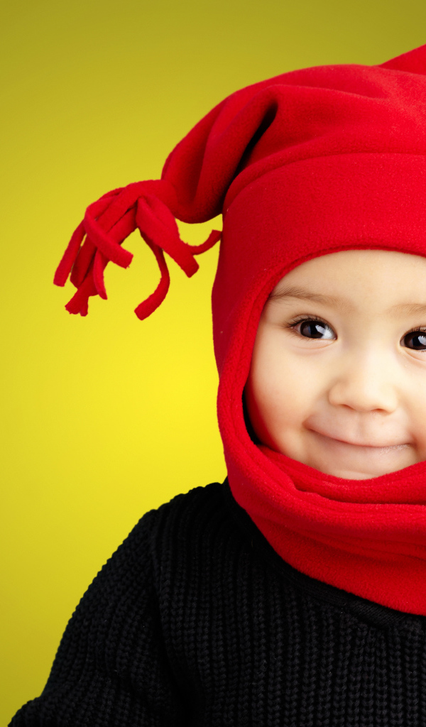 Маленький мальчик в красной шапке и в черном свитере