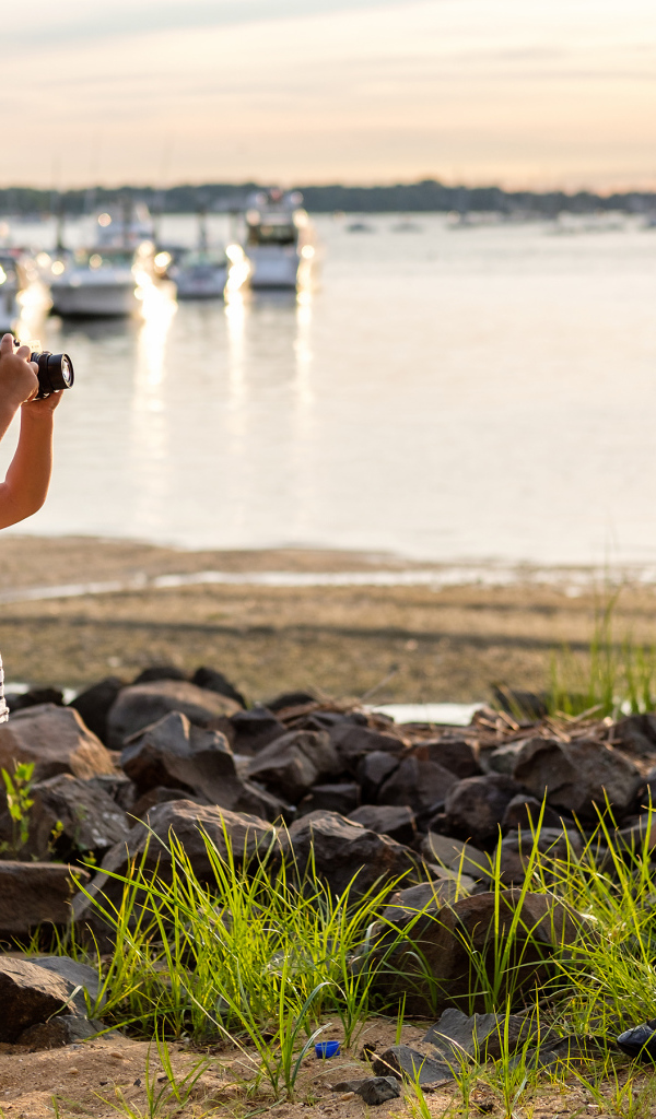 Маленький мальчик фотографирует девочку на берегу