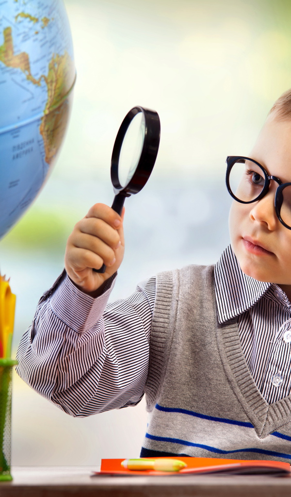 Маленький мальчик в очках исследует глобус