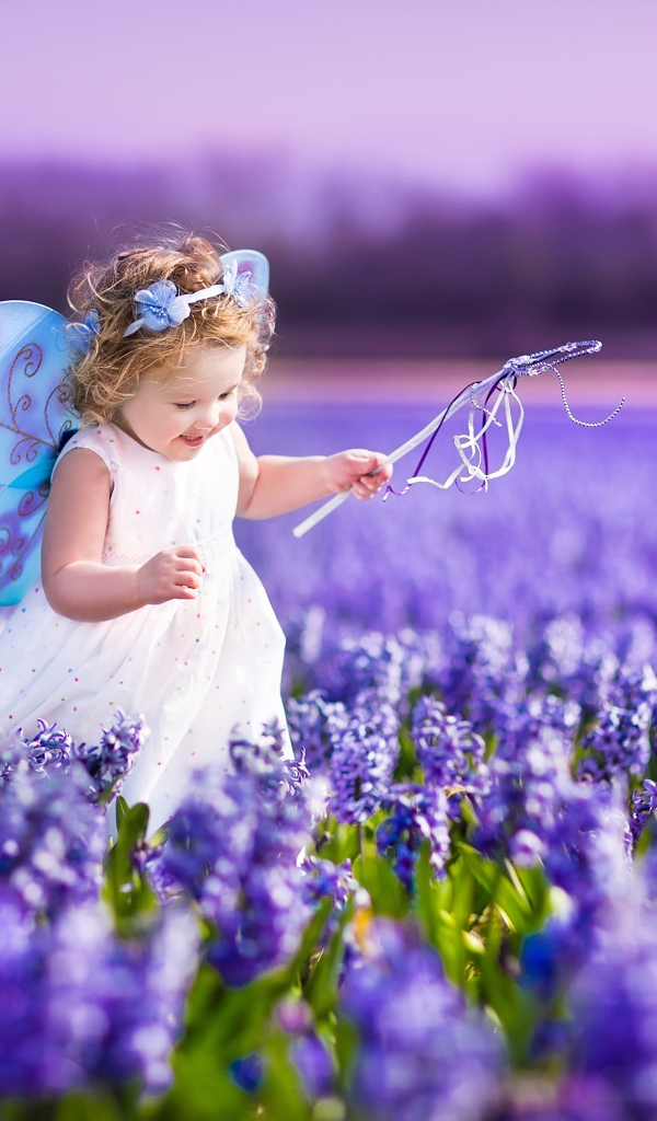 Маленькая девочка в костюме феи гуляет по полю гиацинтов
