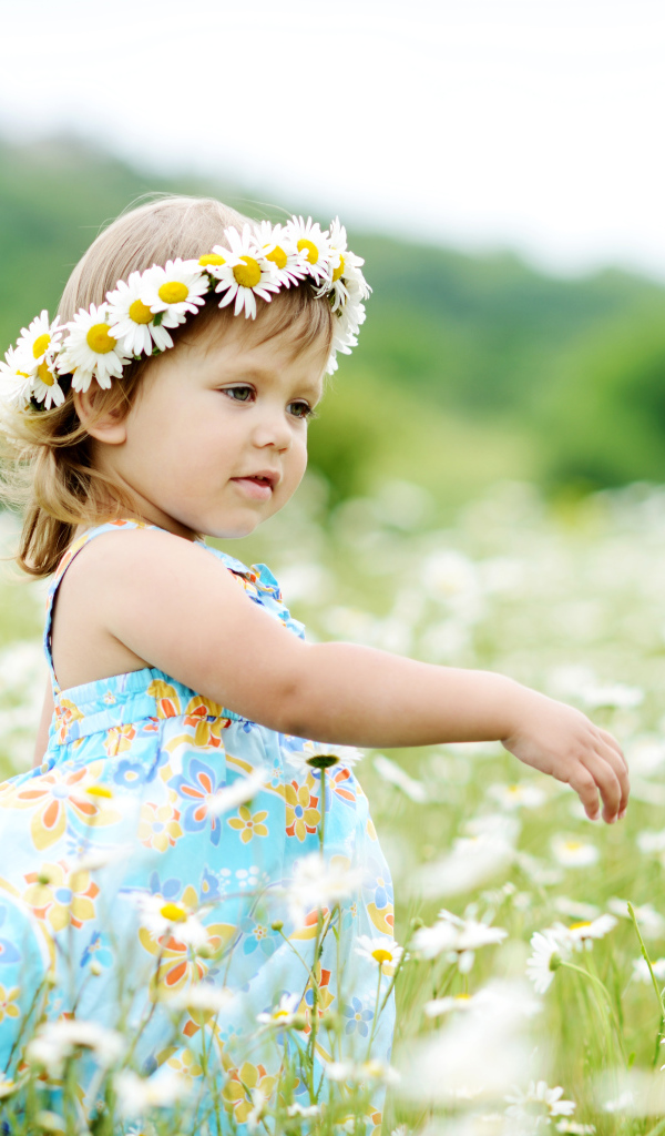 Маленькая девочка в сарафане гуляет по полю с ромашками летом
