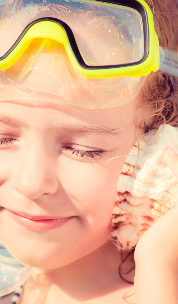 Маленькая девочка приложила ракушку к уху