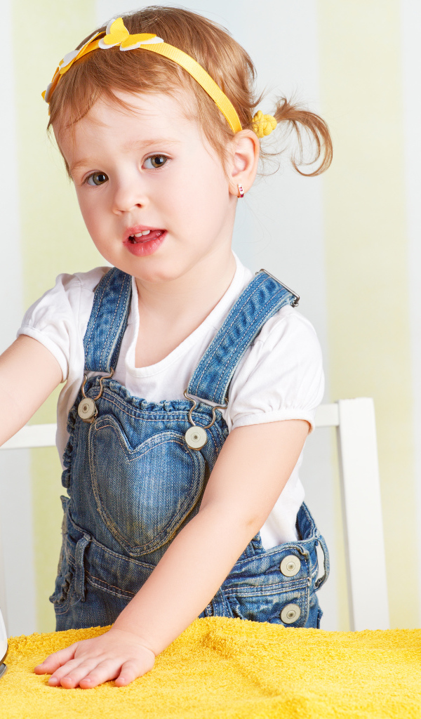 Маленькая девочка с утюгом гладит полотенце