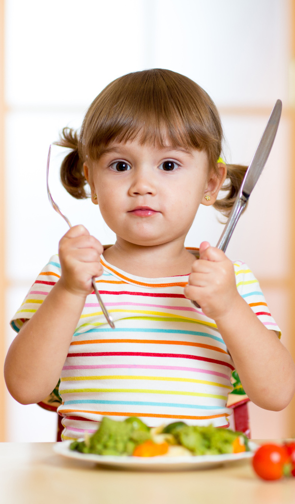 Маленькая девочка со столовыми приборами и тарелкой