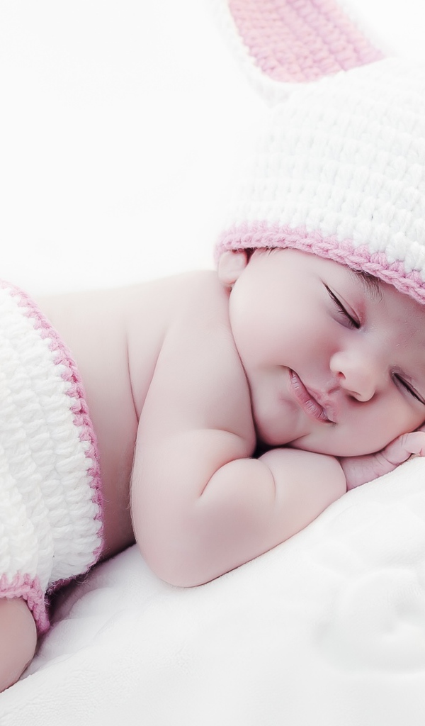 Маленький спящий ребенок в вязаном костюме зайчика