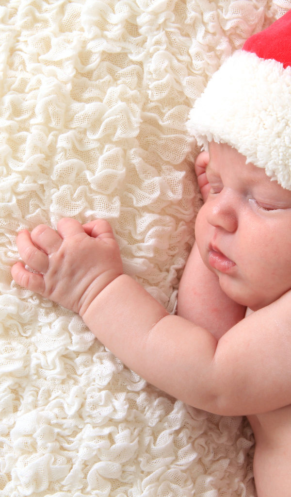 Маленький спящий ребенок в красном новогоднем колпаке
