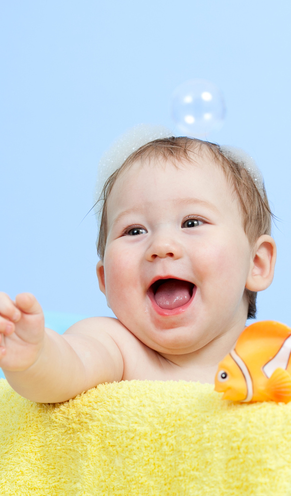 Веселый малыш купается в ванной с игрушечной рыбкой