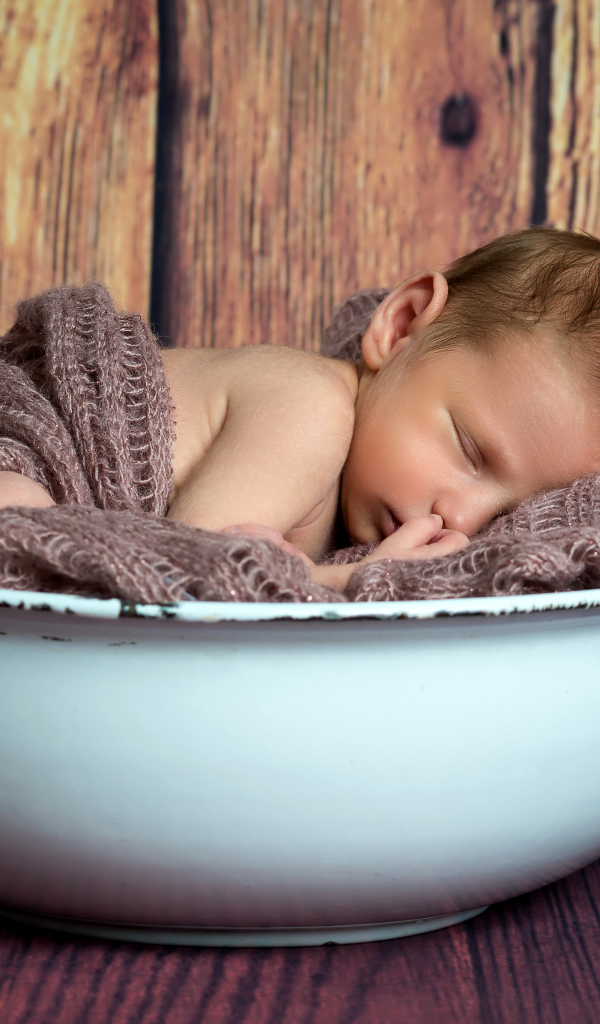 Новорожденный ребенок спит в белой миске