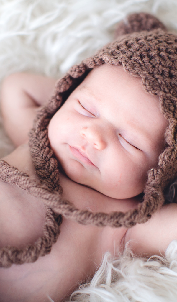 Спящий младенец в вязаной коричневой шапке