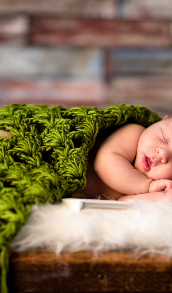 Спящий младенец под зеленым вязаным пледом