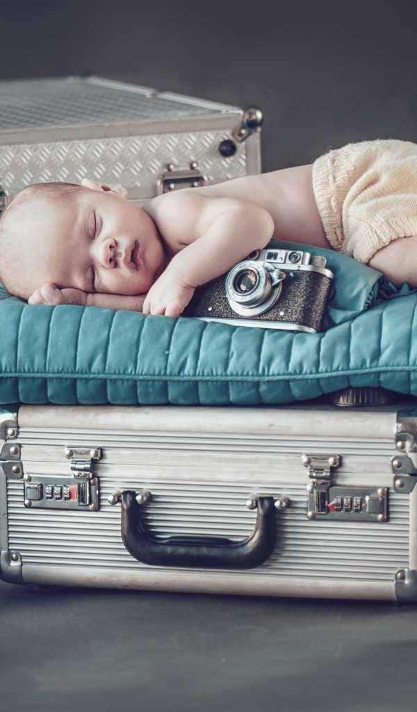 Спящий младенец с фотоаппаратом спит на чемодане