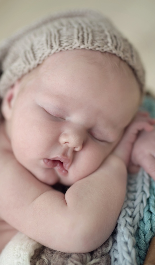 Маленький грудной ребенок спит в вязаной шапке