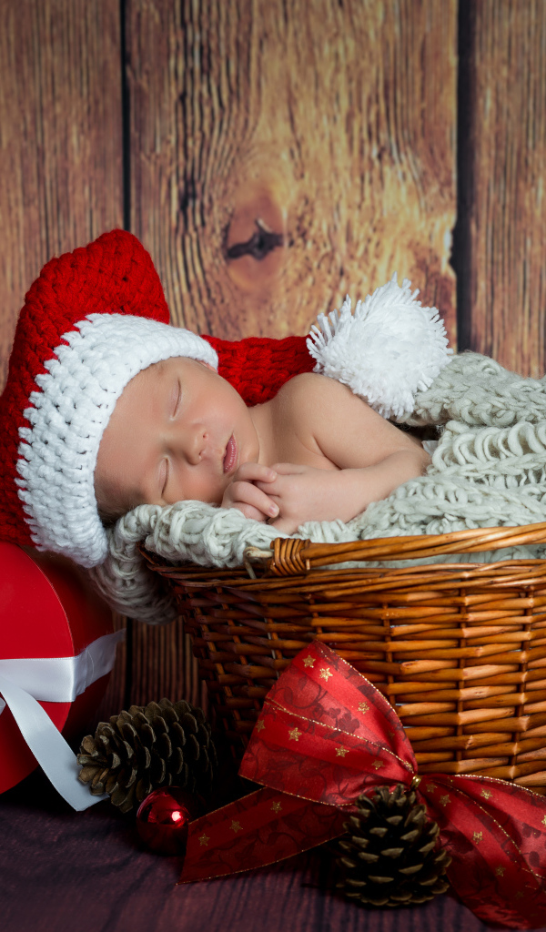 Маленький грудной ребенок спит в плетеной корзине с новогодними подарками