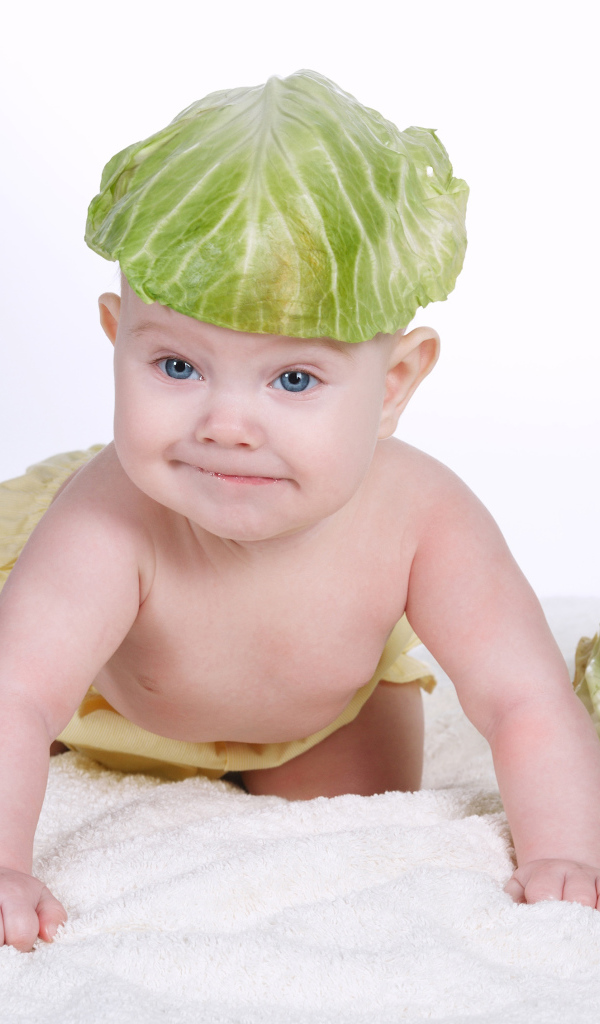 Маленький грудной ребенок с капустным листом на голове