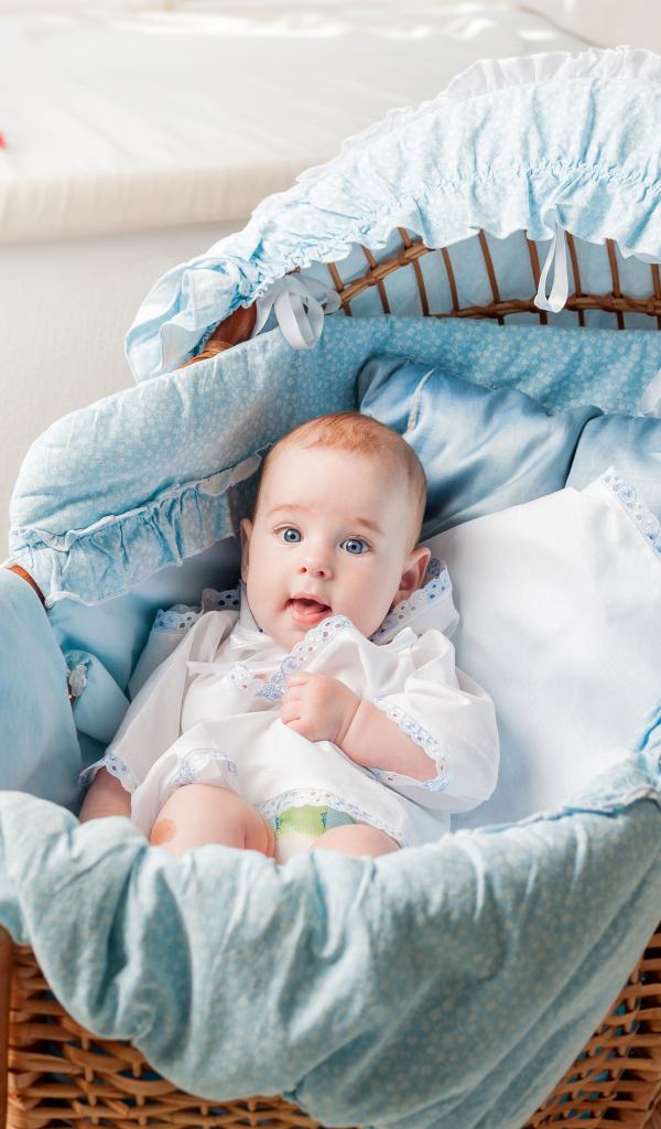 Маленький голубоглазый младенец в кроватке