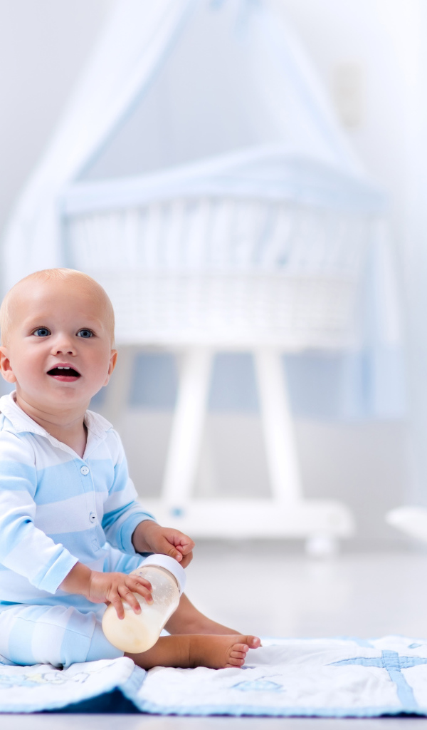 Маленький голубоглазый мальчик сидит на полу в комнате