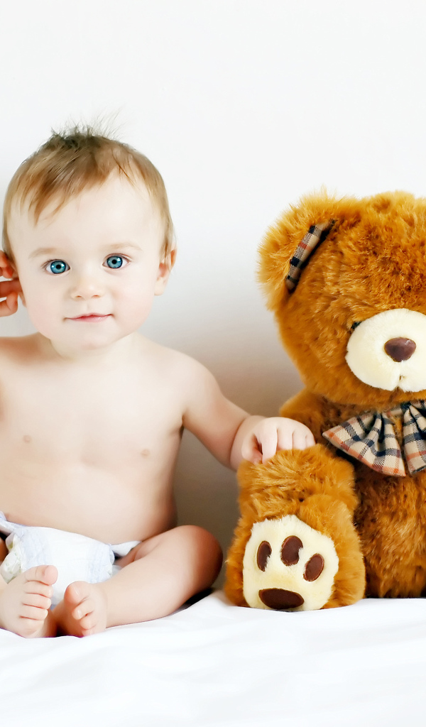 Маленький голубоглазый ребенок с большим плюшевым медведем