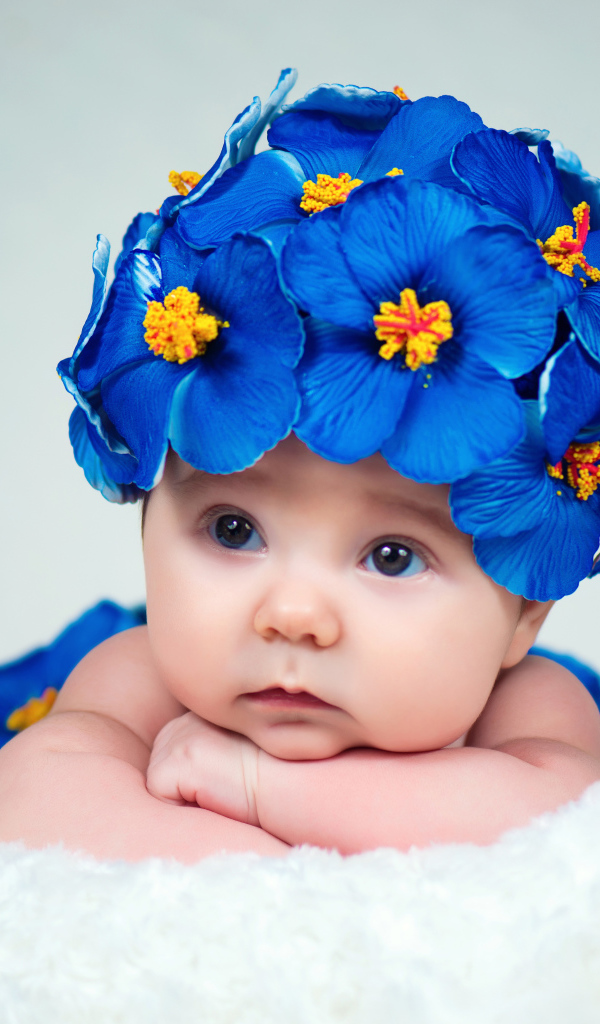 Маленький ребенок в красивой шапке с голубыми цветами