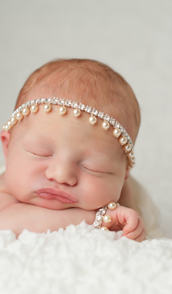 Маленький спящий грудной ребенок с красивым украшением на голове