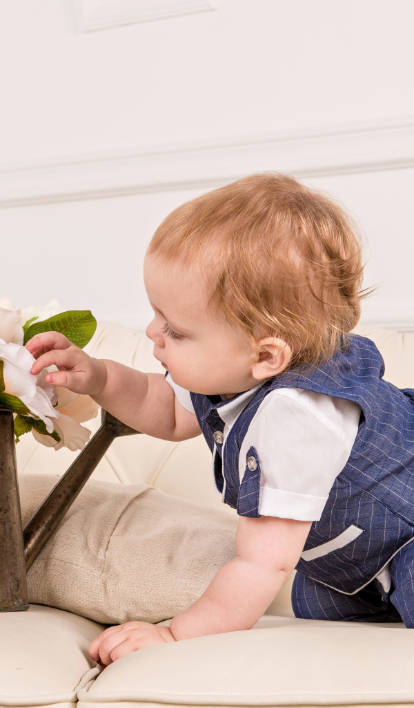 Маленький ребенок рассматривает цветы в железной лейке