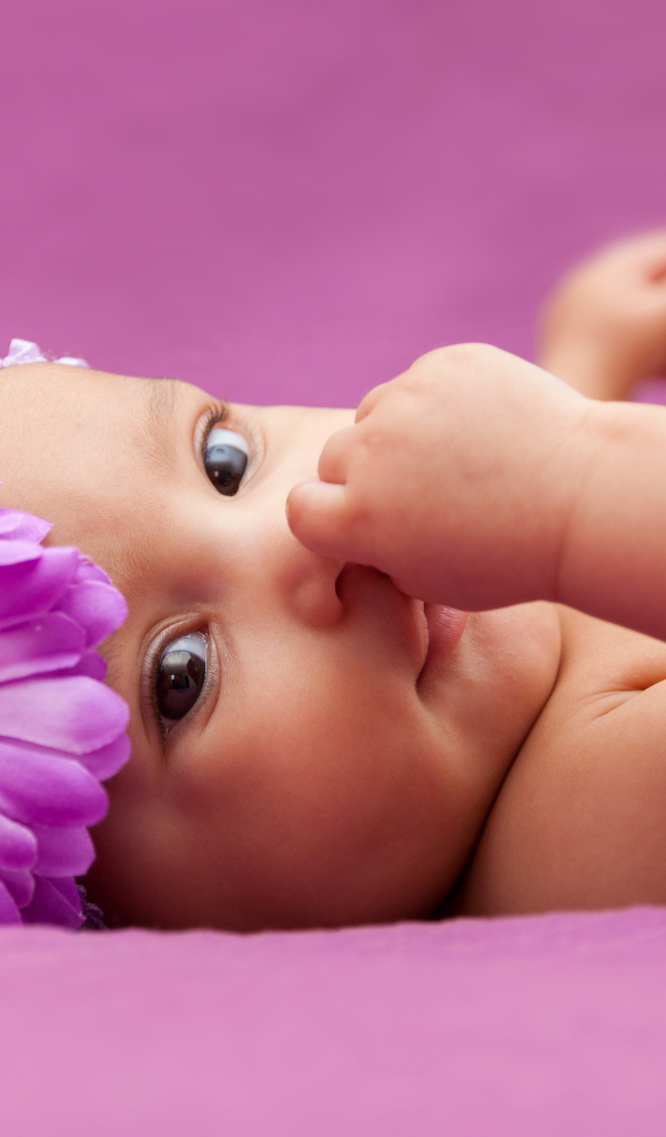 Младенец девочка с большим сиреневым цветком на голове 