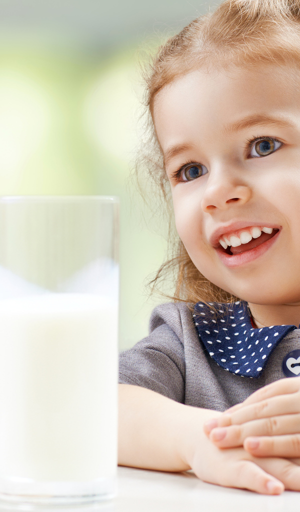Красивая кареглазая девочка со стаканом молока