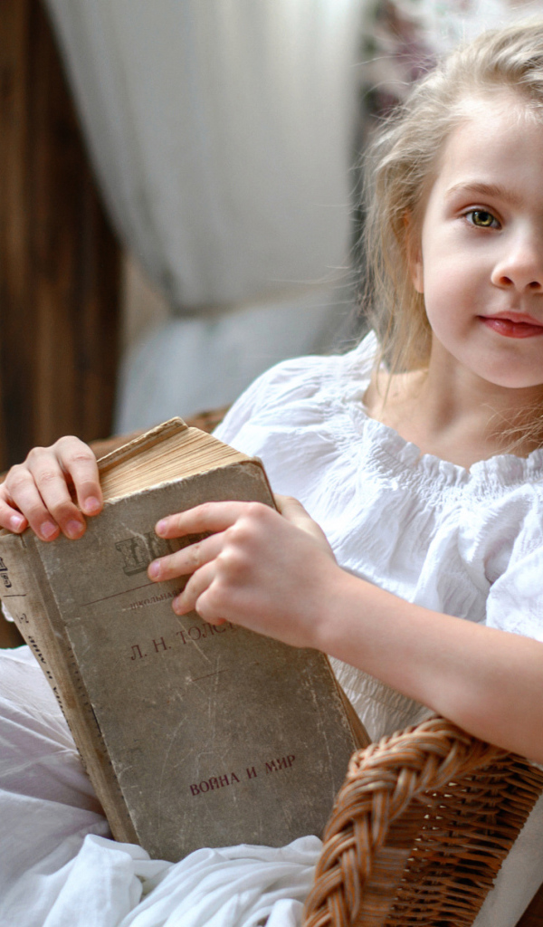 Красивая маленькая девочка в белом платье с книгой 