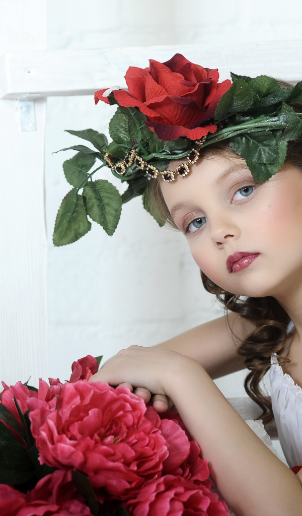 Красивая маленькая девочка с венком из роз на голове