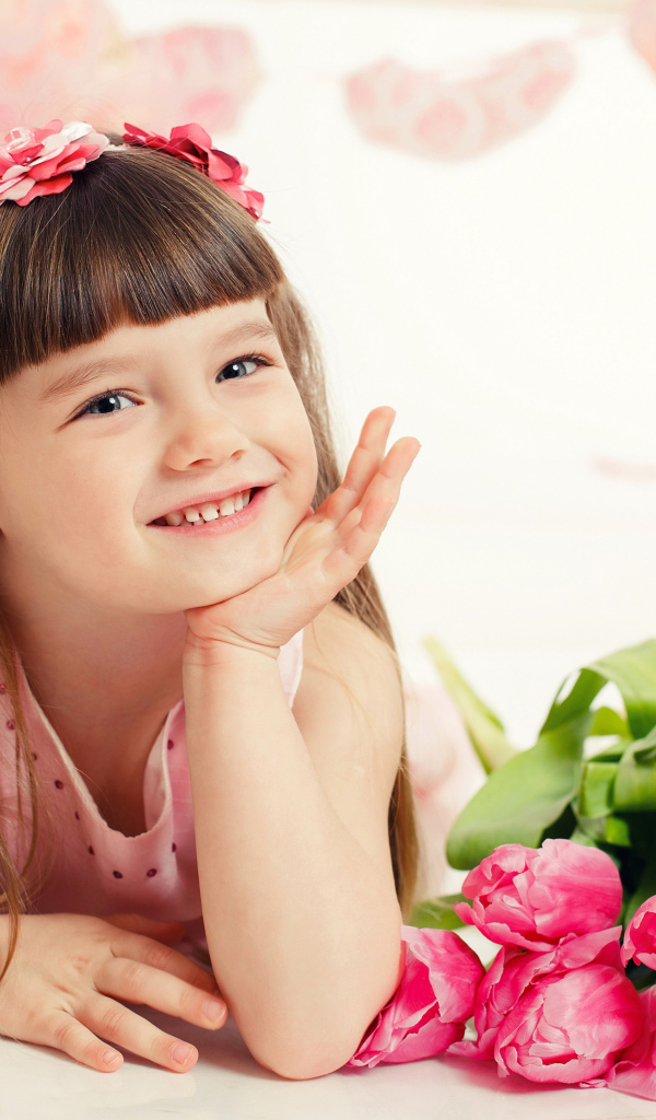 Красивая длинноволосая улыбающаяся девочка с букетом розовых тюльпанов