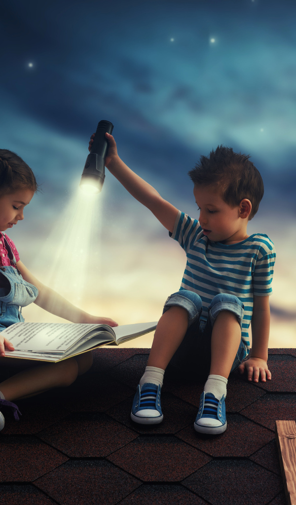 Мальчик и девочка ночью читают книгу на крыше