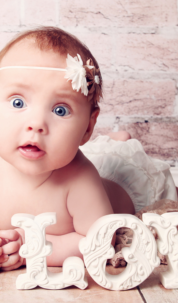 Грудной ребенок с надписью любовь на фоне кирпичной стены