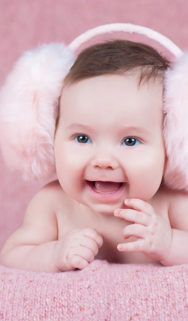 Милый улыбающийся младенец в больших розовых наушниках