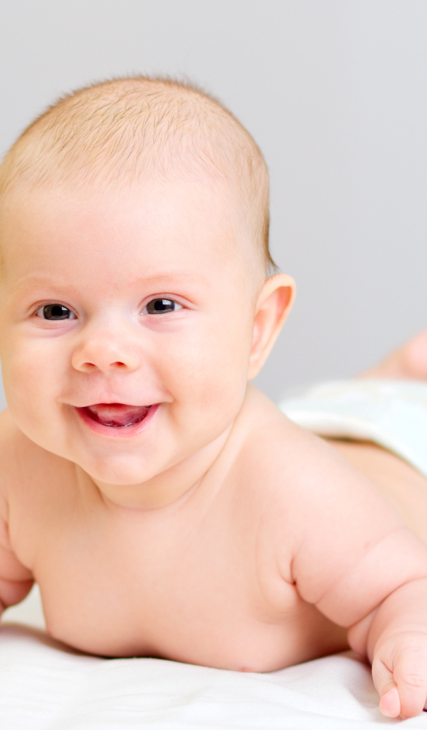 Милый улыбающийся ребенок на сером фоне