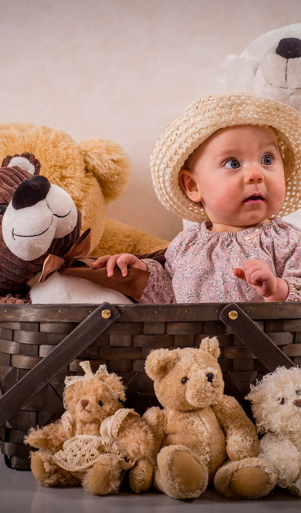 Забавный грудной ребенок в корзине с мягкими игрушками