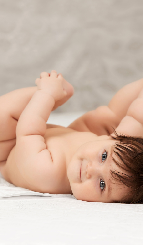 Забавный младенец держится руками за ноги 