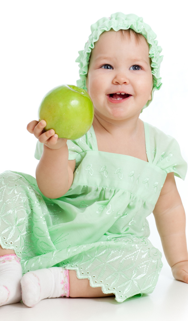 Маленькая голубоглазая девочка с зеленым яблоком в руках