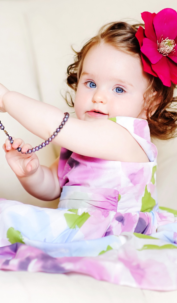 Маленькая голубоглазая девочка с красным цветком в волосах