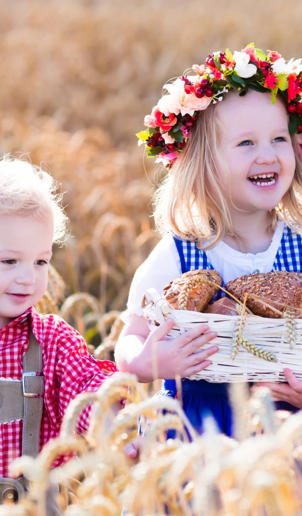 Маленькие мальчик и девочка на поле пшеницы с корзиной свежей выпечки
