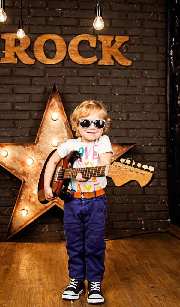 Маленький мальчик в модных очках с гитарой