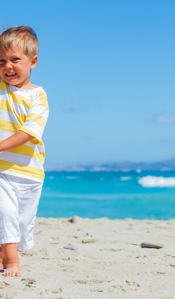 Маленький мальчик на пляже с игрушечным самолетом в руках