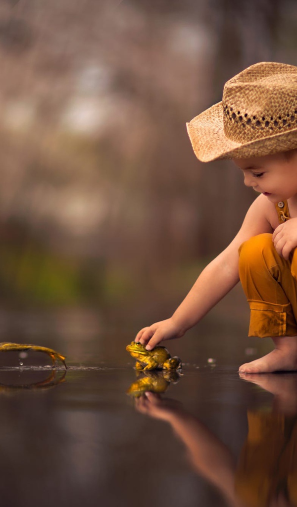 Маленький мальчик играет с лягушками 