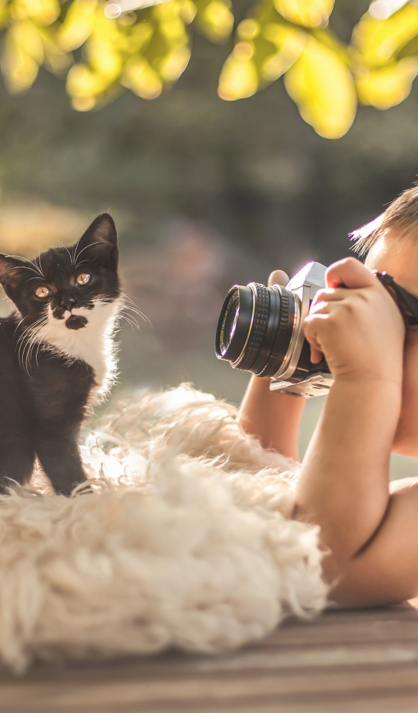 Маленький мальчик фотографирует котенка