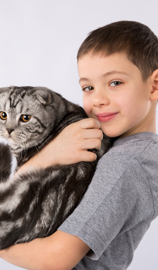 Маленький мальчик с большим котом на сером фоне