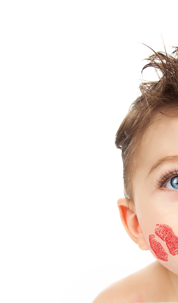 Маленький мальчик со следами от поцелуев на лице на белом фоне